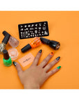 A woman's hand alongside China Glaze nail lacquer with Nail Art Ghoulish Stamping Kit