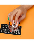 China Glaze Nail Art Ghoulish Stamping Kit featuring a woman's hand wearing a different color of nail polish