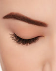 A model wearing Ardell's Ecolashes 453 on a closed right eye showing its extra-long layers with intense volume and fullness