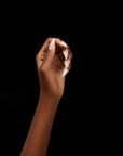 A hand elegantly posed with glossy white almond-shaped nails against a sleek black background.