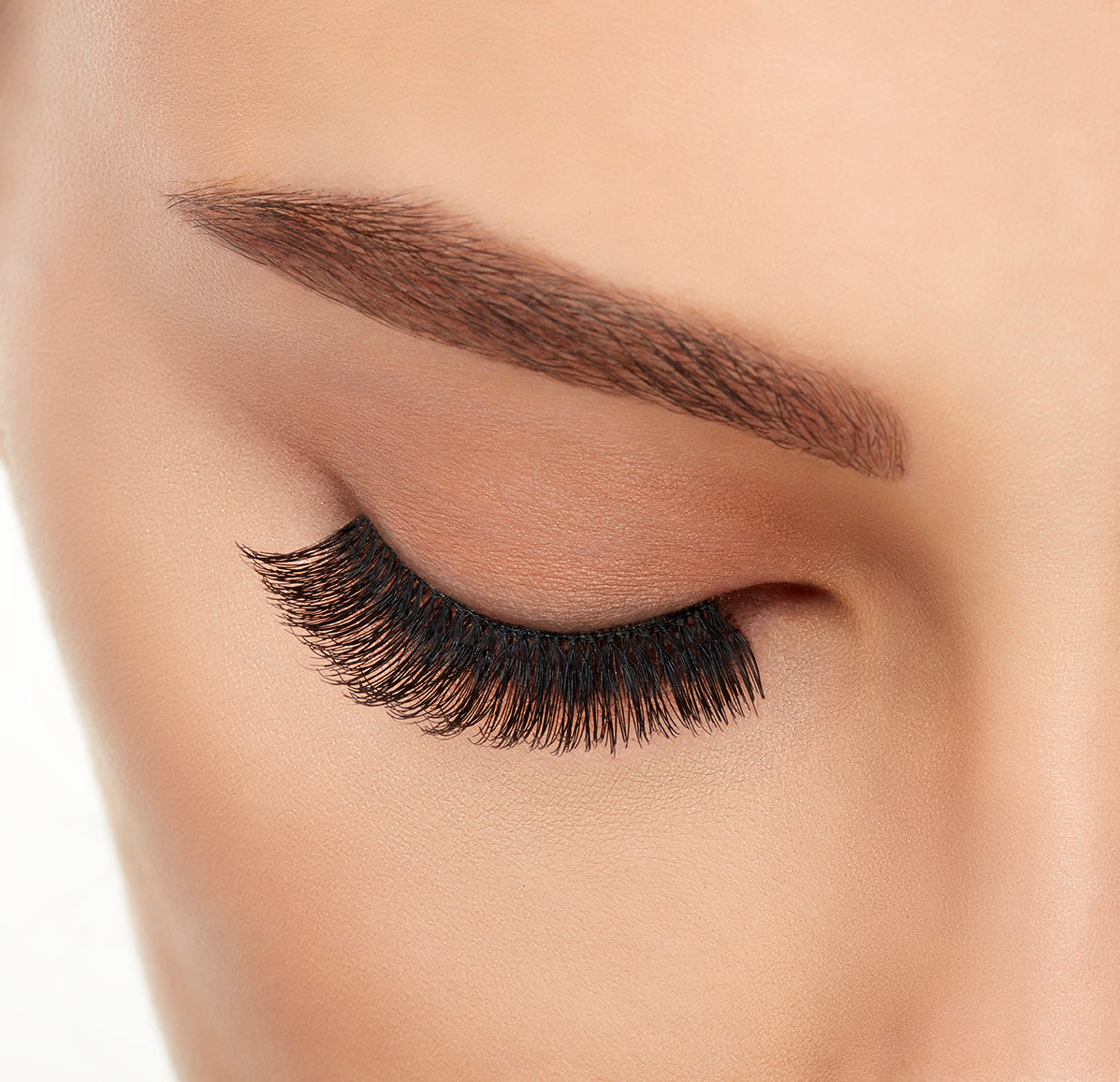 A model with closed eye wearing Ardell Studio Effects 105 with full volume, long length & natural lash look