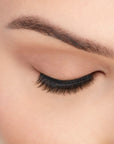 An extreme front shot of closed eye wearing a Fauxmink 815 by Ardell creating a natural, elongated & curly lash