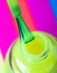 A view of nail enamel bottle with nail brush on top in a multi-colored background