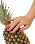 A woman touching a pineapple revealing her almond shape colored nails