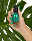 A woman with medium skin tone fingers and hand-holding green citrus revealing her colored nails