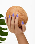 A woman's hand holding a coconut emphasizing her almond shape nails