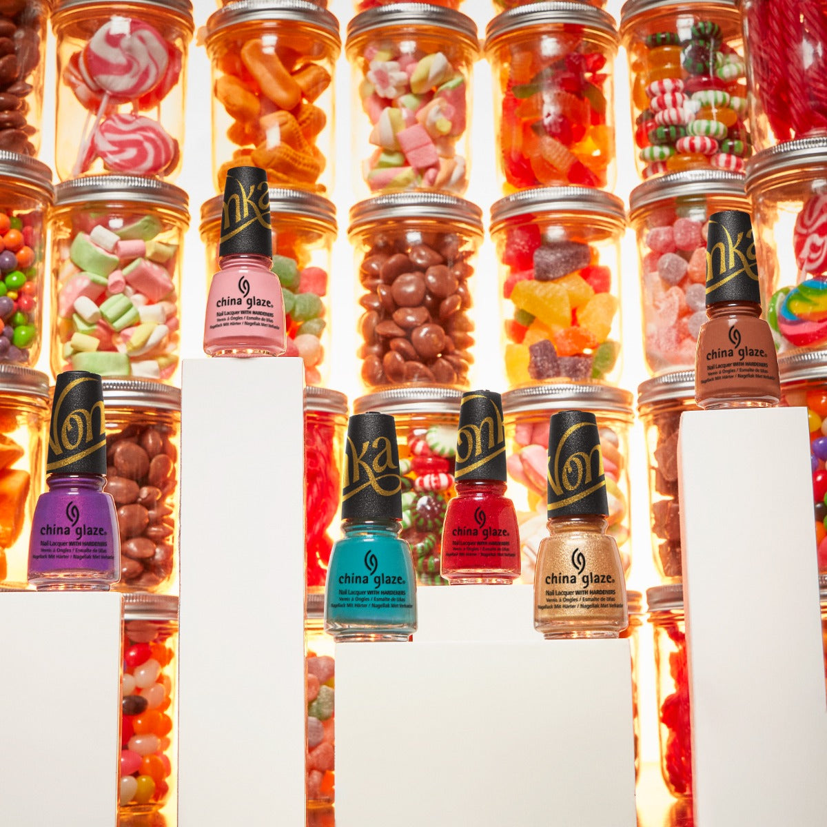 China Glaze Wonka collection with colorful nail polish bottles displayed in front of a candy-filled background.