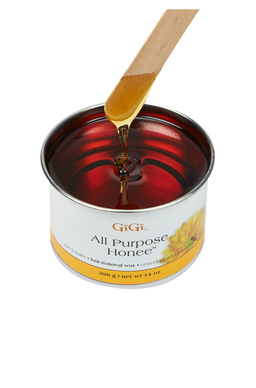 Wax applicator being drawn from an open can of GiGi All Purpose Honee featuring its honey-like color and thick consistency