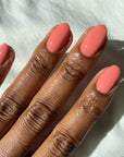 Dark skin tone Fingernails of a lady revealing her pink coral crème nail treatment