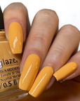A woman's hand showing a glimpse of Tangerine Heat color nail polish in her nails while holding a nail lacquer bottle