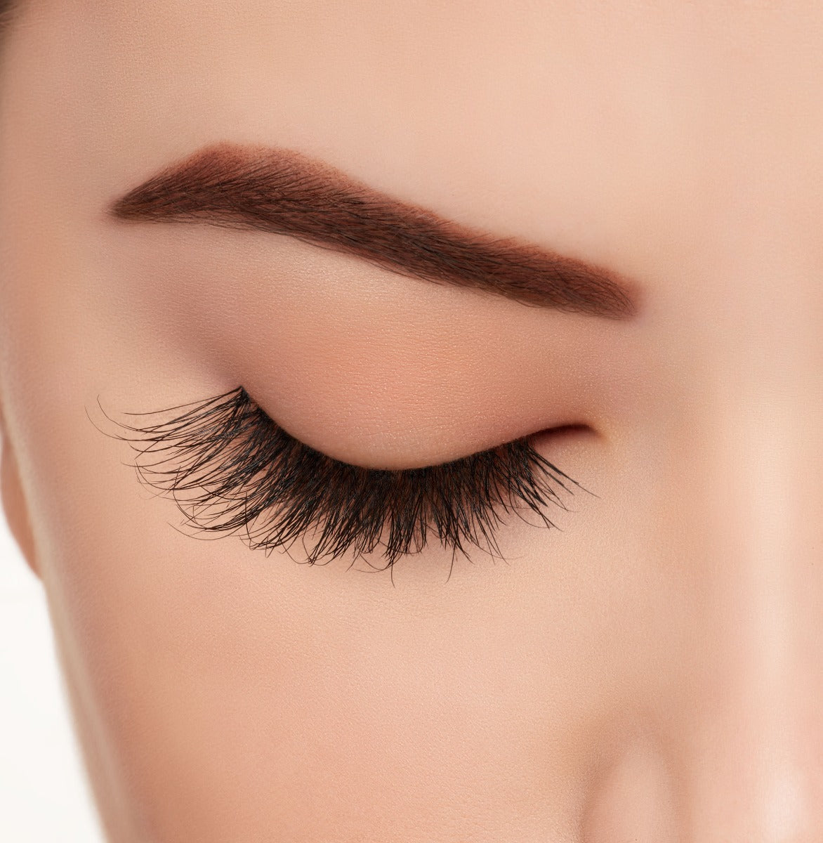 A woman wearing Ardell's Wispies 703 with a closed right eye featuring its medium-length, full volume lash effect