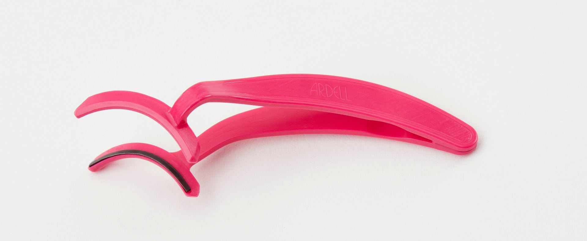 Pink Ardell Magnetic Lash Applicator laying on its side, fully opened with black strip on its head.