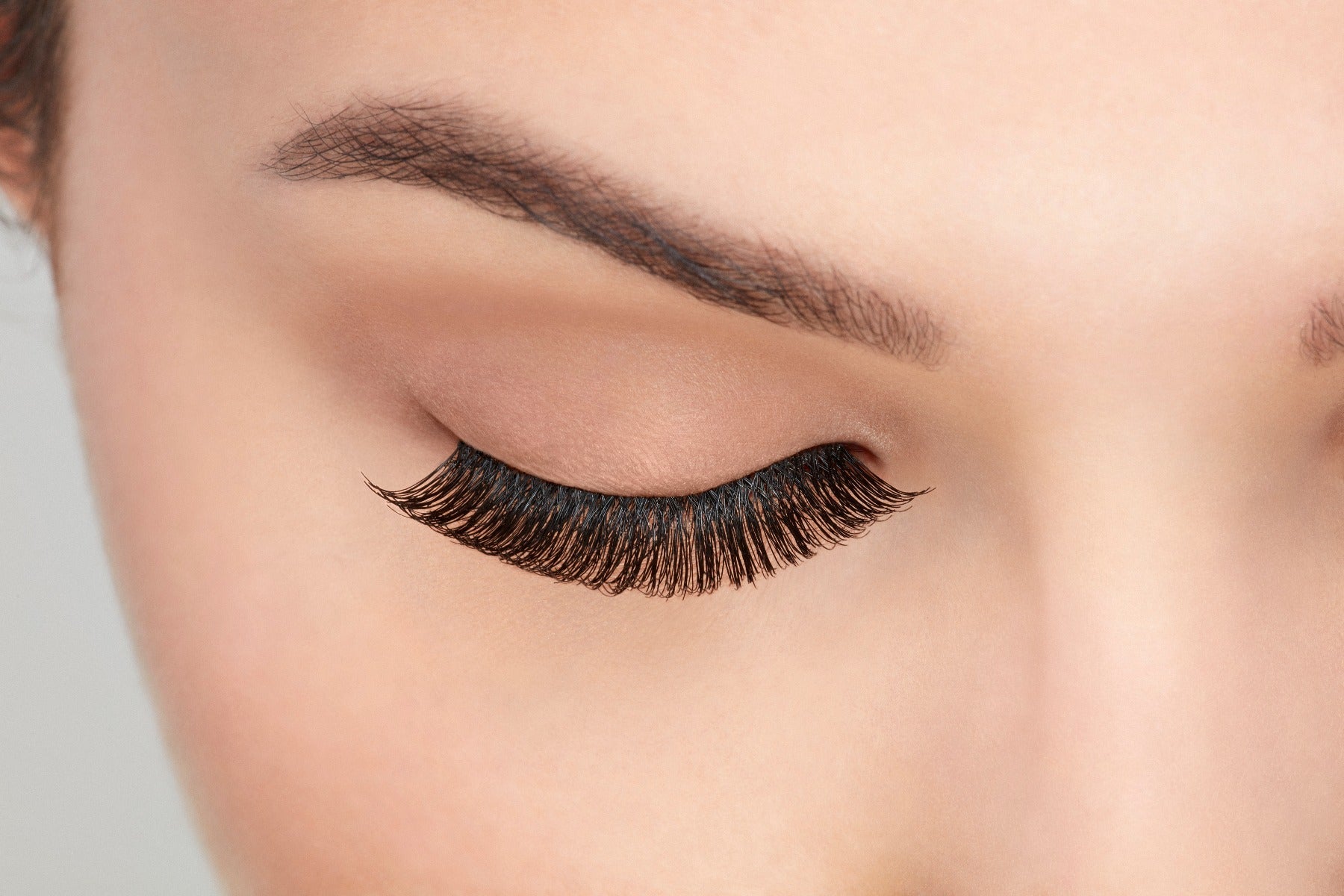 A model with a close right eye wearing Ardell Natural 105 showing how it looks undetectable & totally natural look