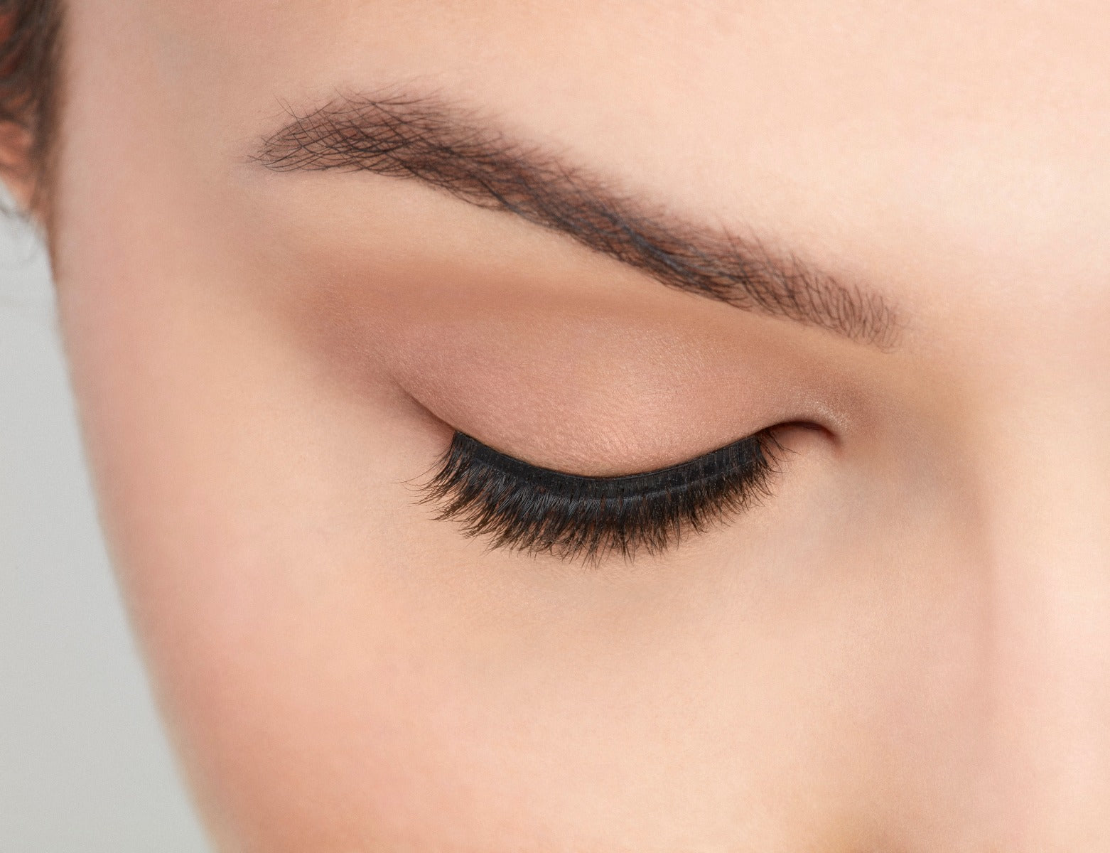 An extreme front shot of closed eye wearing a Fauxmink 815 by Ardell creating a natural, elongated &amp; curly lash