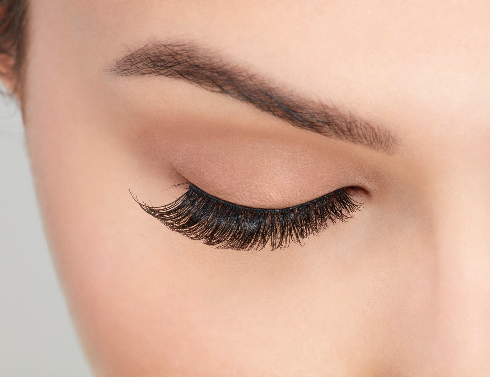 A model with closed eye wearing Ardell Studio Effects Demi Wispies with an accented full volume, curl & natural lash look