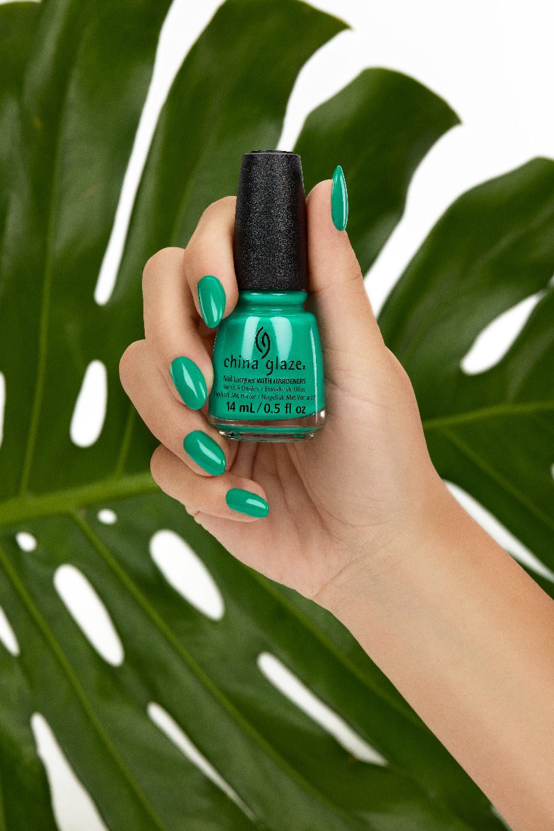 A woman with medium skin tone fingers and hand-holding green citrus revealing her colored nails