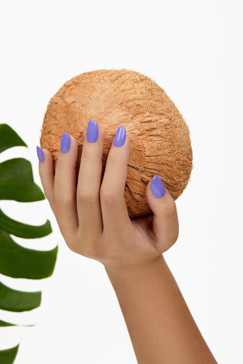A woman's hand holding a coconut emphasizing her almond shape nails