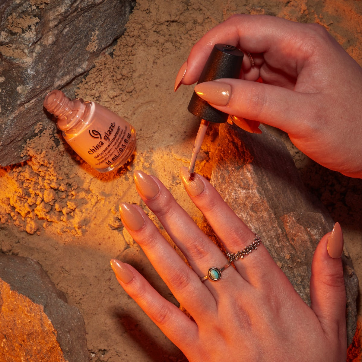 Hand model image putting on shade Dunescape Sand, a red-orange with orange shimmer. 
