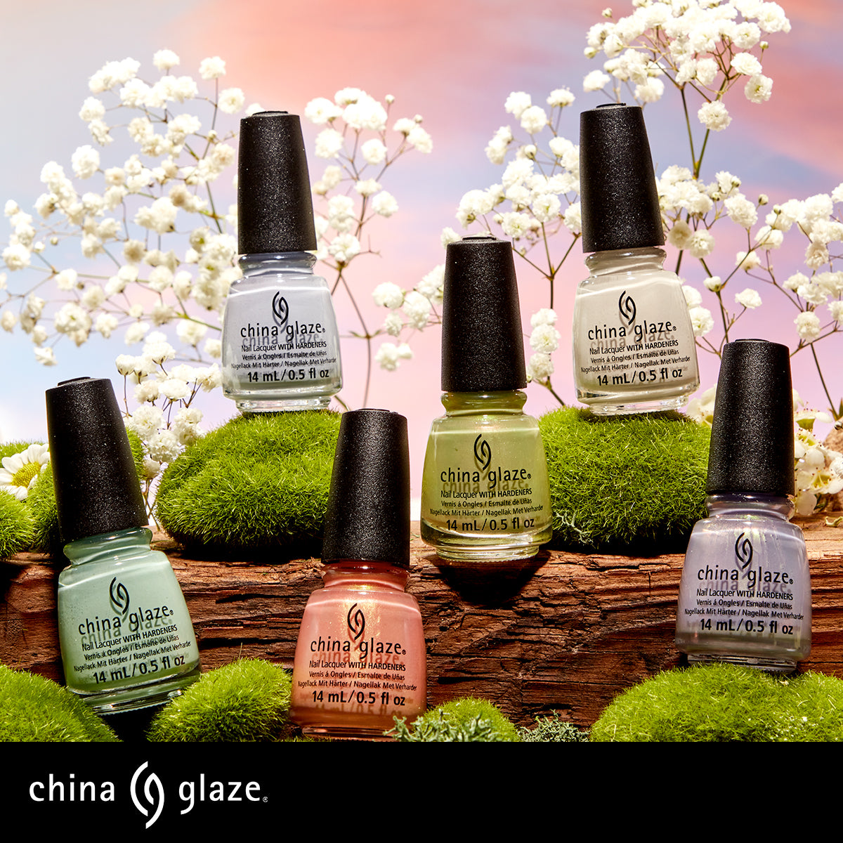 Set of China Glaze pastel nail polish bottles displayed on moss-covered surfaces with white flowers against a soft pink gradient background.
