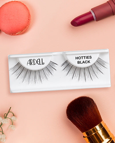 Ardell Hotties Black false eyelashes in packaging with beauty accessories for an elegant lash look.