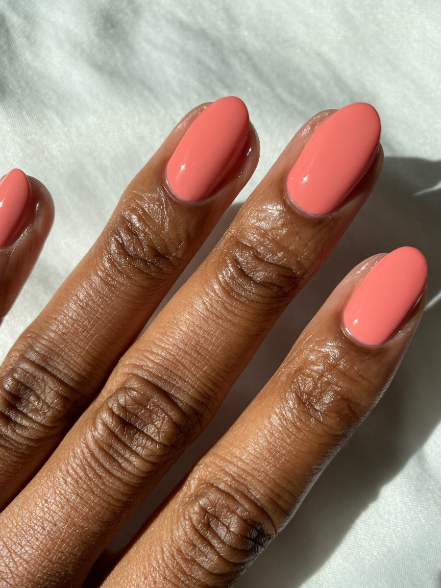 Dark skin tone Fingernails of a lady revealing her pink coral crème nail treatment
