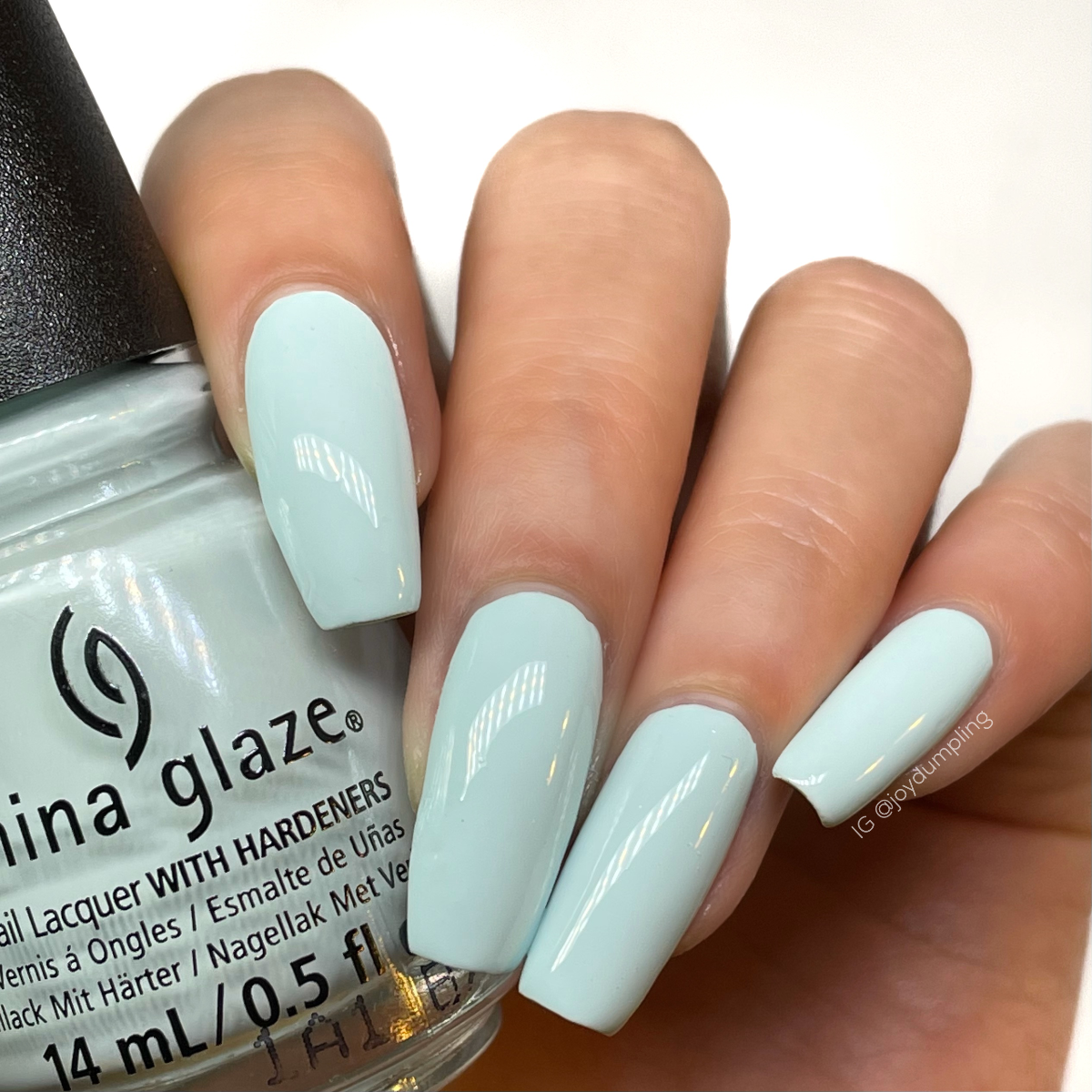 A lady's hand holding nail enamel from China Glaze showing her nail color in coffin-shaped nails